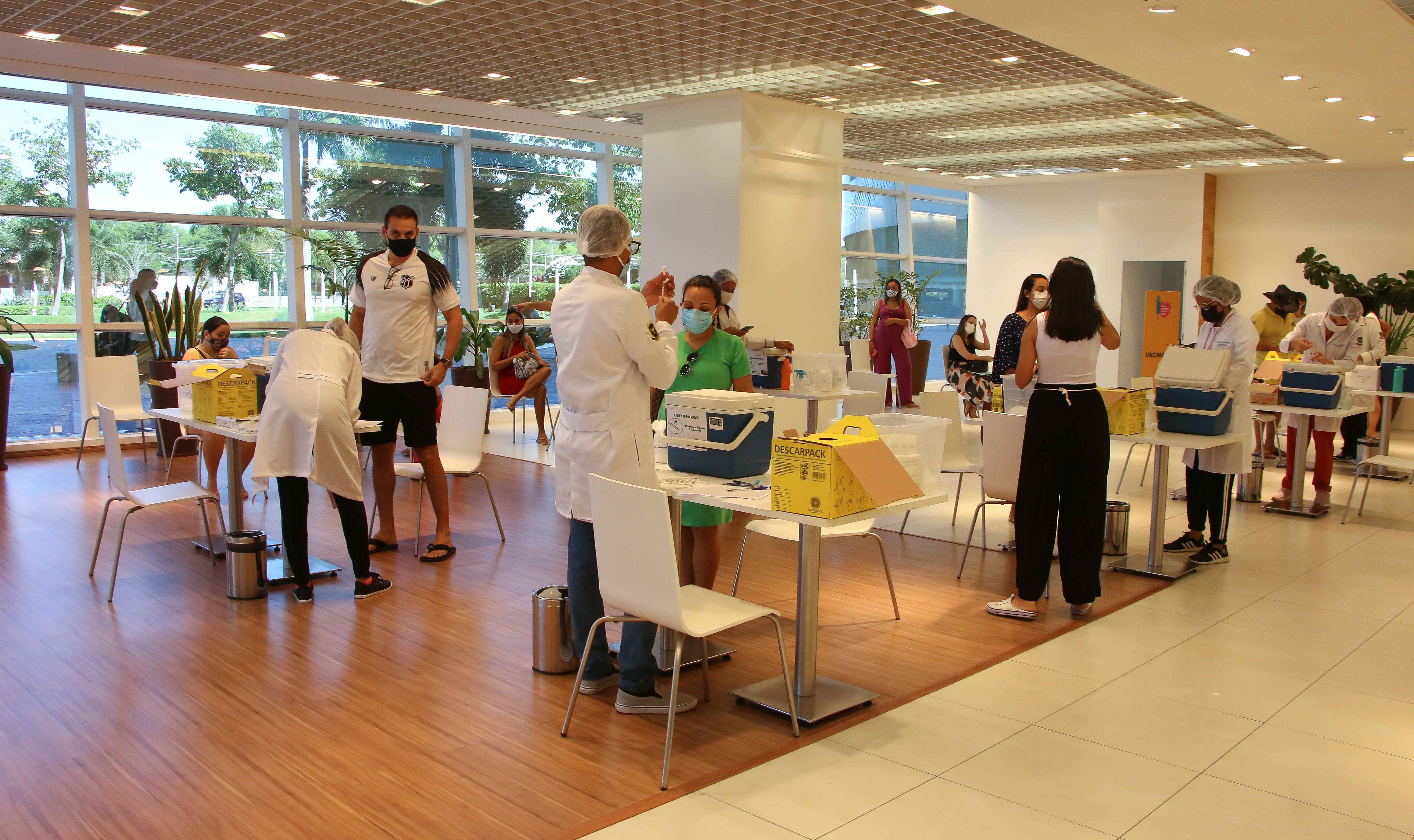 a foto mostra o centro de vacinação montado no shopping iguatemi, com pessoas sendo atendidas por profissionais de saúde
